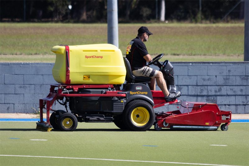 Side view of the SportChamp machine crossing a green synthetic field