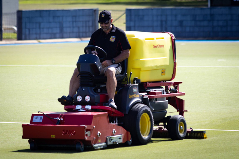 Closer front view of the turf cleaning machine on a green hockey field