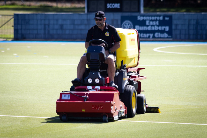 Turf machine heading towards the camera in front of the field scoreboard